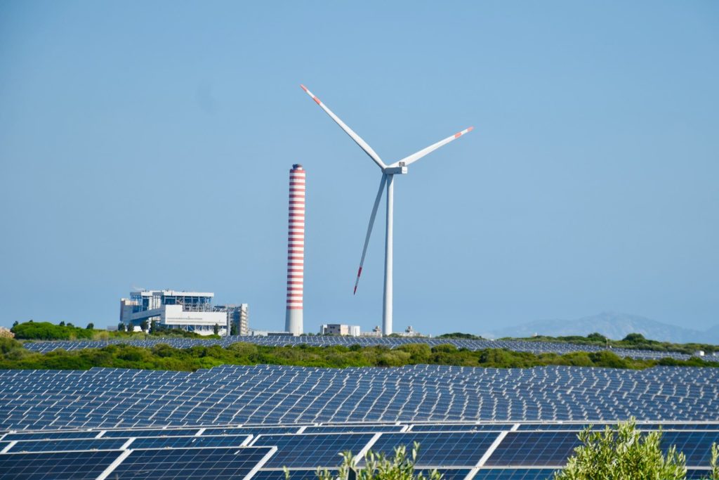 A solar farm with a wind turbine in the background.